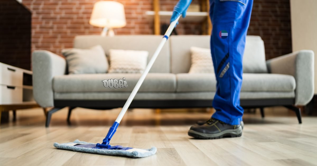 Cleaner mopping a hard floor next to a sofa during a deep clean in a Dubai home