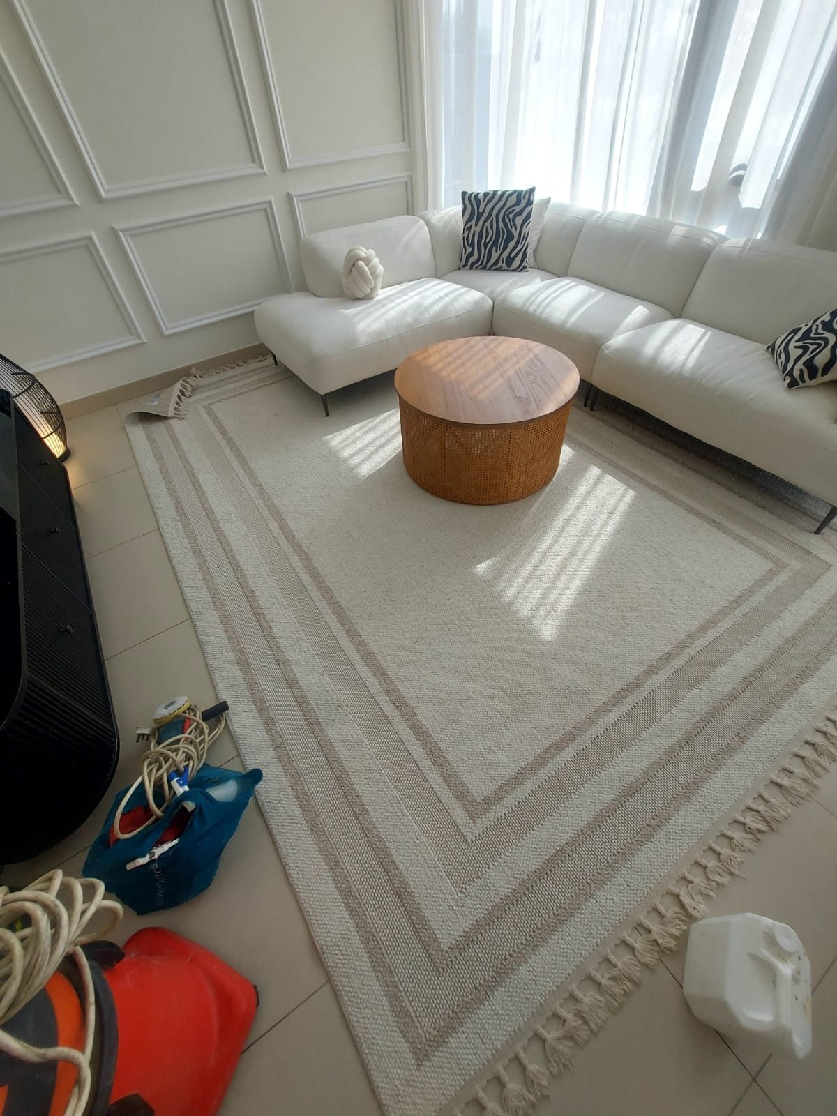 Living room with white sofas and a rug set up for a deep cleaning job in a Dubai villa, with cleaning equipment on the floor